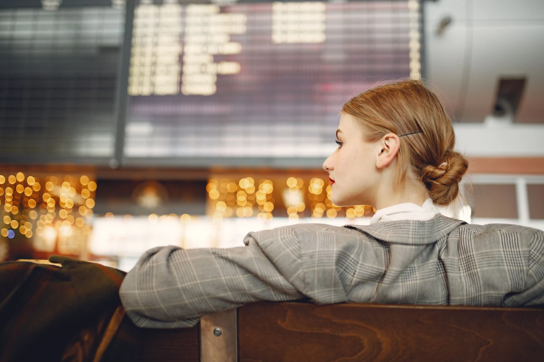 Blurred departure board and a traveller waiting at an airport