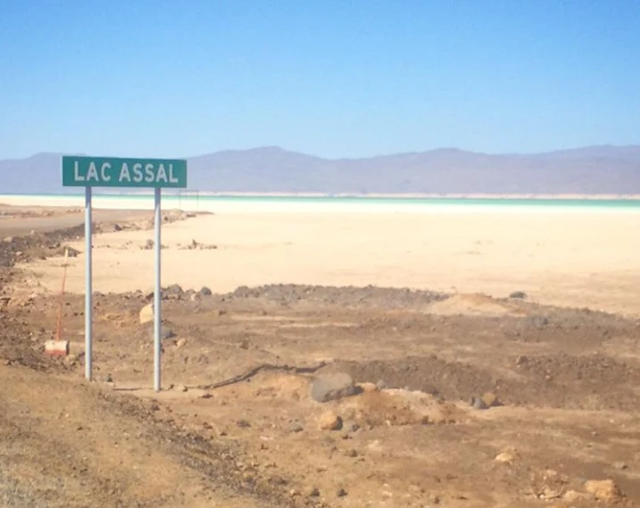 Paved road toward Lake Assal through black lava and arid terrain.