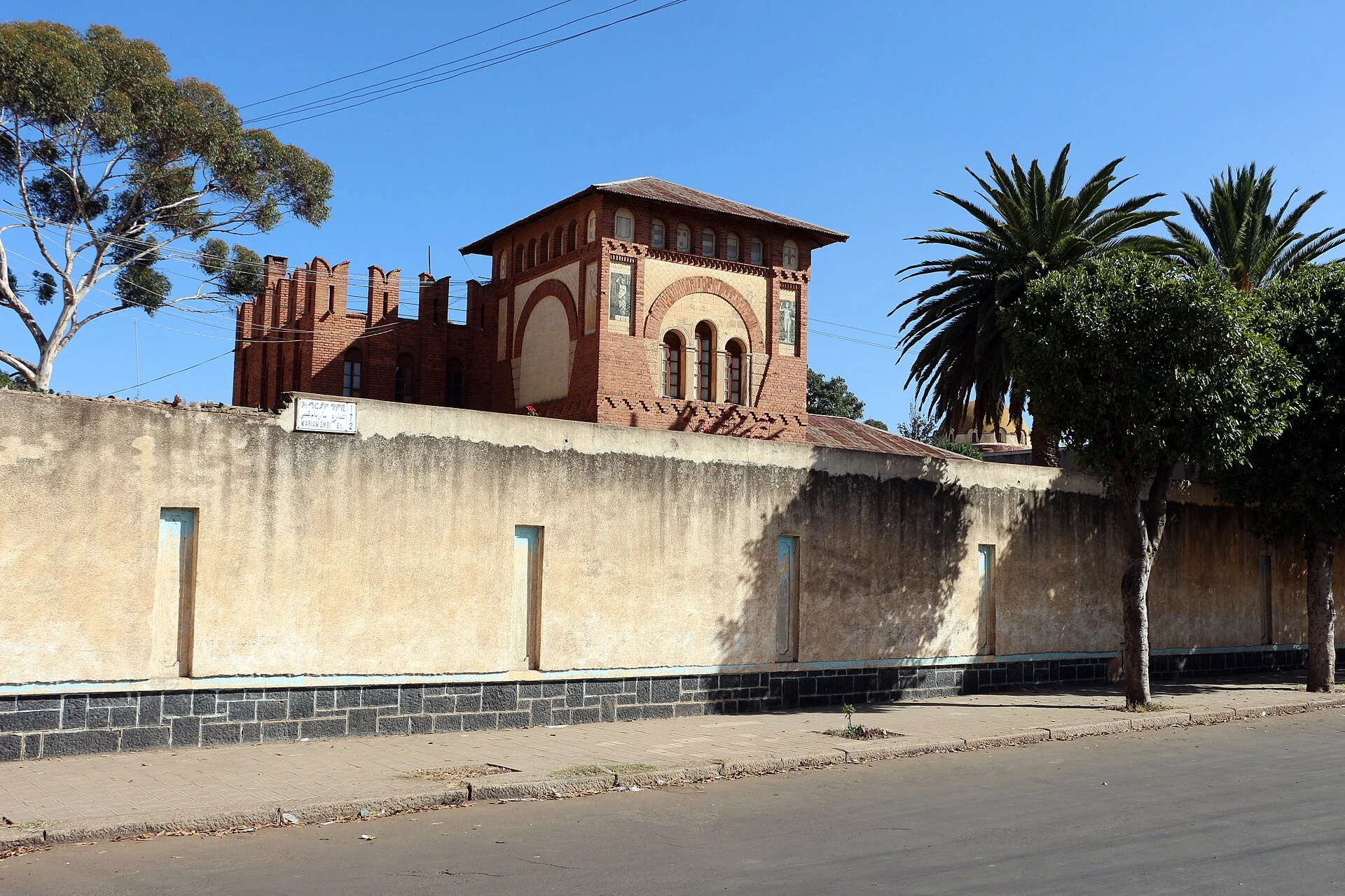 Asmara street with neighborhood shops and religious silhouettes in the distance.