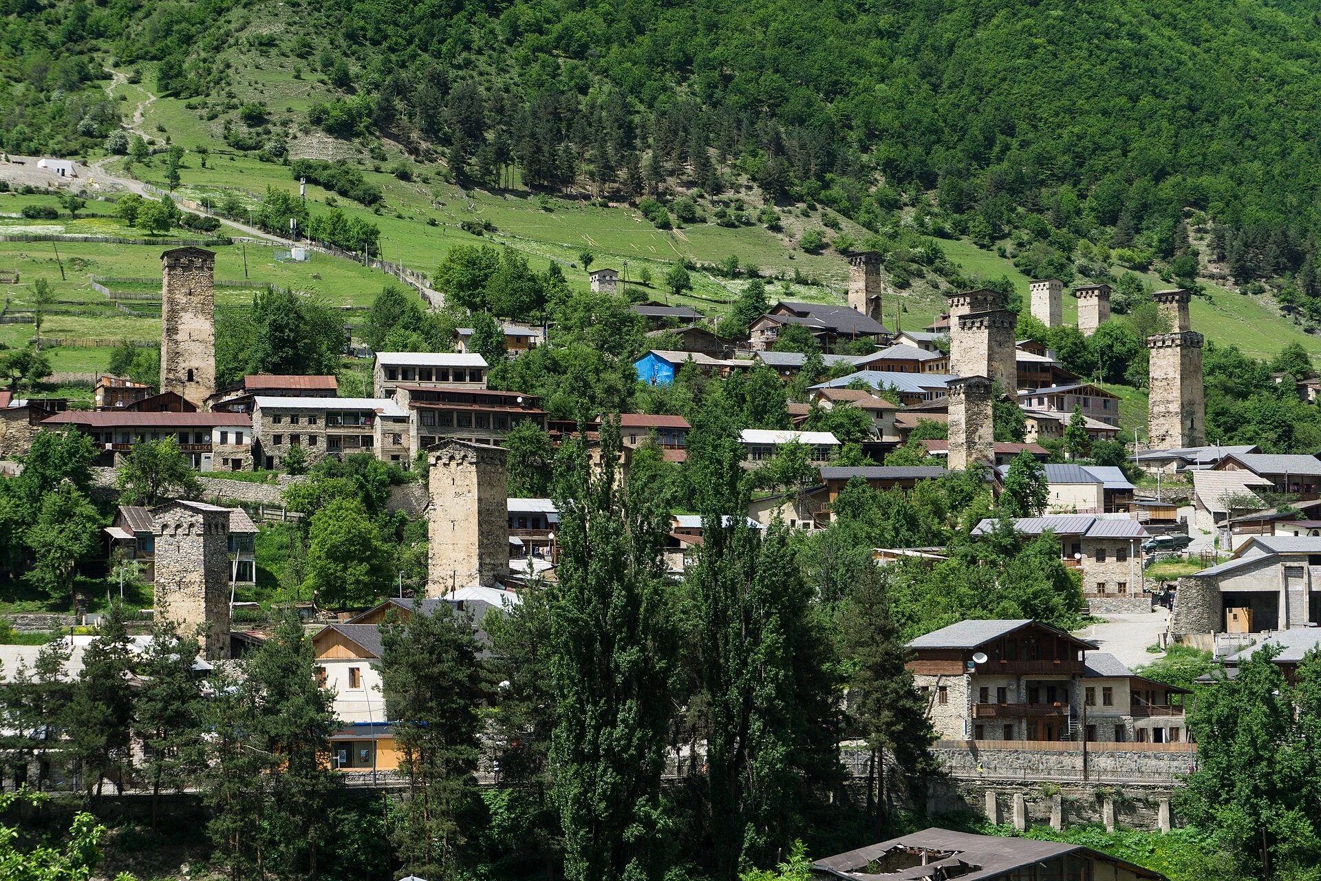 Svan towers and stone houses in Mestia with Caucasus mountains behind.